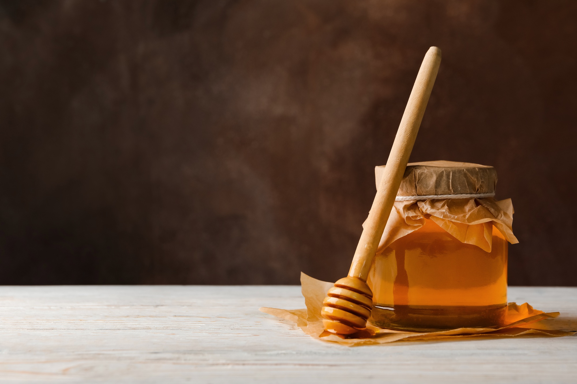 Honeycombs, jar with honey and dipper on wooden background