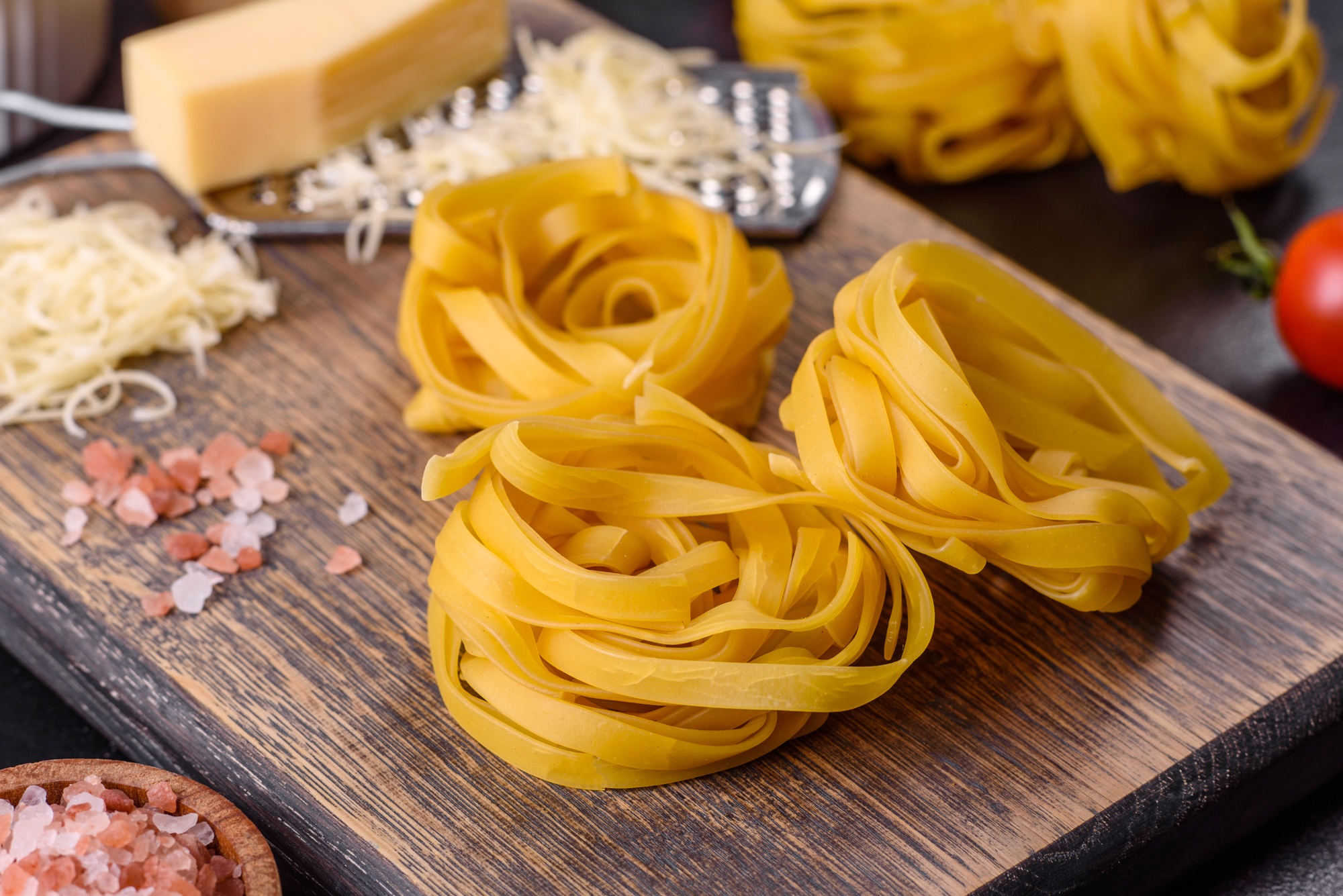 Raw tagliatelle paste with grated cheese, cherry tomatoes, spices and herbs